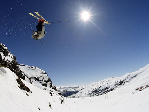 En alpinist tar en backflip på ski i snøfylte omgivelser